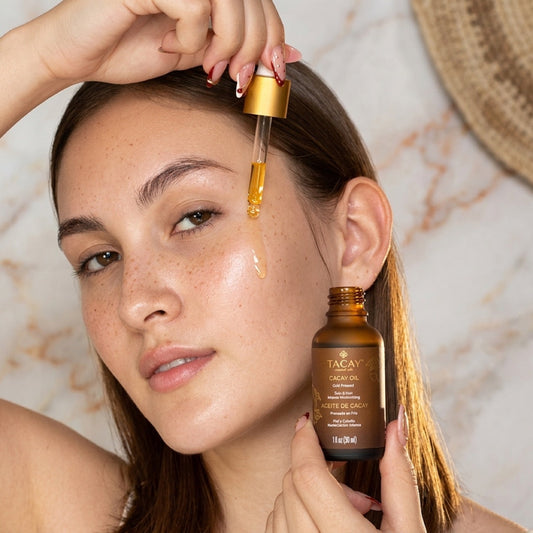 Close-up of a woman with freckles applying cacay oil, a natural retinol alternative